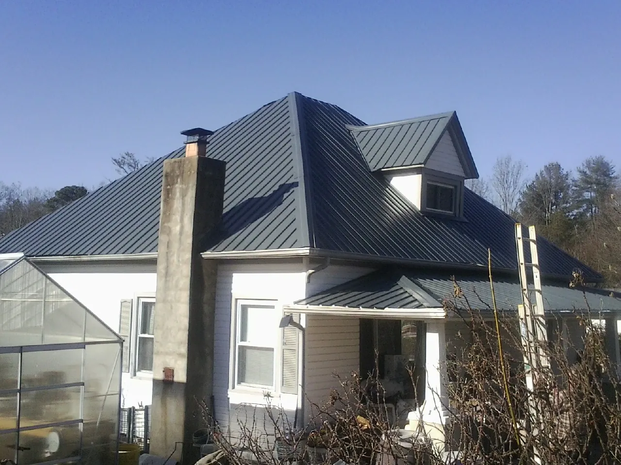 Dark blue standing seam metal roof on a white farmhouse with dormer — Slate & Tile Roof Repair by Roofing Brothers in Aliquippa