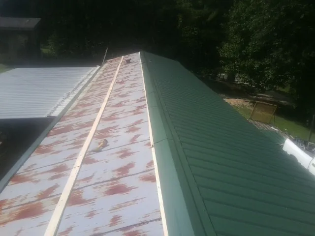 Old rusted panels beside newly installed green metal roofing — Wind Damage Roof Repair by Roofing Brothers in Aliquippa