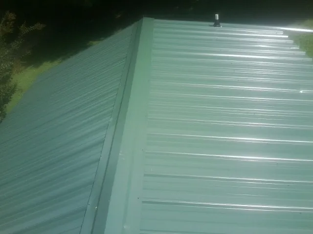 New green metal panels meeting at the ridge of a roof — Flat Roof Repair work by our crew in Aliquippa