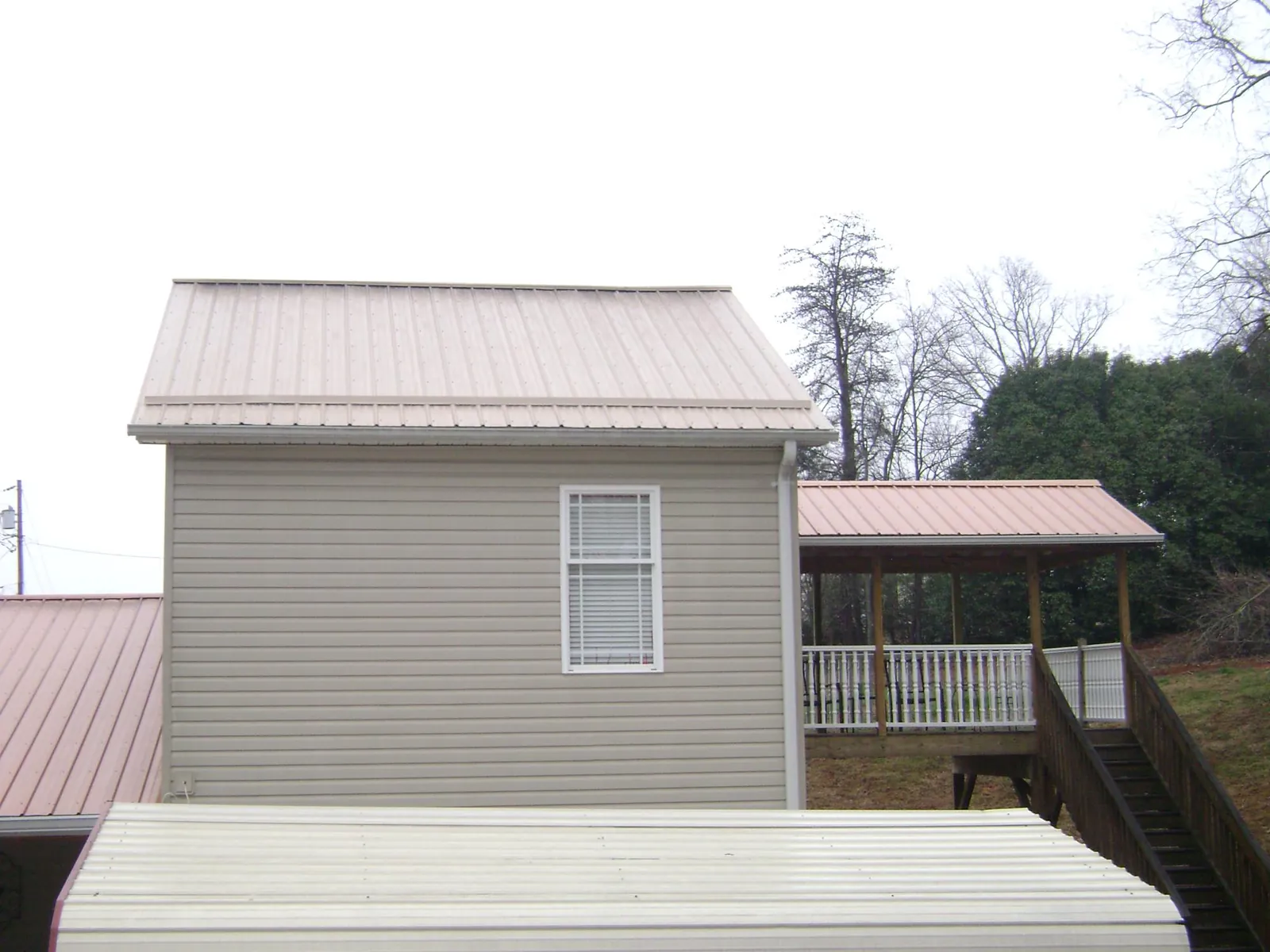Tan metal roofs on a two story addition and attached porch, from a Roof Replacement job in Aliquippa