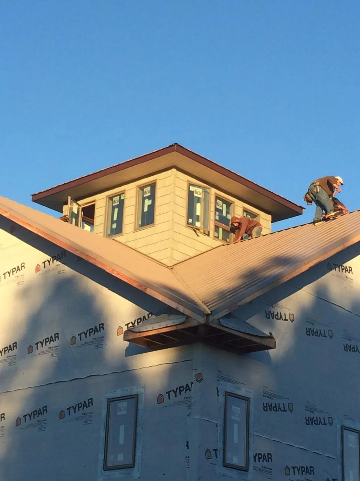 Roofers working around a rooftop cupola on a new metal roof at sunset — Roof Waterproofing in Aliquippa by Roofing Brothers